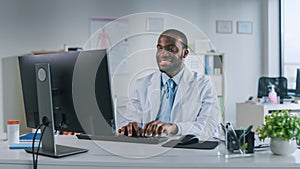 Happy Smiling African American Medical Doctor is Working on a Computer in a Health Clinic. Physici