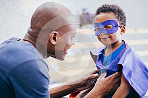 Happy smiling African American son being supported and helped by supportive father