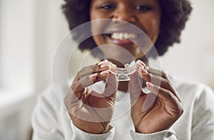 Happy, smiling African American woman holding a plastic tray for teeth whitening