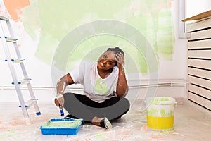 Happy smiling african american woman painting interior wall of new house. Redecoration, renovation, apartment repair and