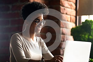 Happy African American woman using laptop, chatting with friends