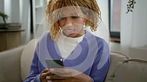 Happy smiling African American woman using smartphone reading pleasant news shopping online with cellphone girl social