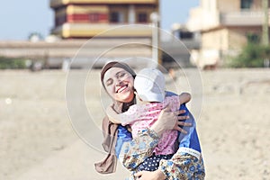 Happy smiling arab muslim mother wearing islamic hijab hug her baby girl in egypt