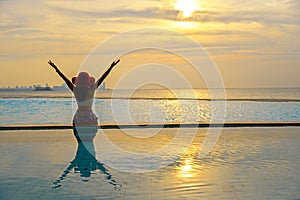 Happy smiling asia woman with straw hat relax and luxury in swimming pool, background sunset.