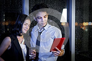 Happy smiling Asian business man and woman working together, look at digital tablet and have discussion, employee working hard