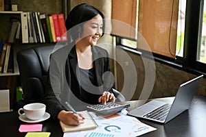 Happy Asian businesswoman is satisfied with her business income while calculating sales