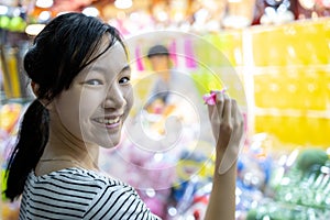 Happy smiling asian child girl holding a dart,looking at camera,  having fun, female teen playing the dart game with balloons for