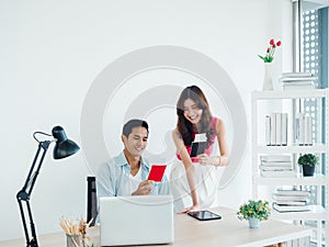 Happy smiling Asian couple, young man and woman holding passport and flight tickets after booking online.