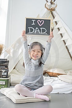 Happy smiling Asian daughter holding & x22; I LOVE DAD & x22; background si