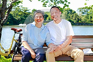 Happy smiling Asian elderly couple Sit in an outdoor park on a nice day.