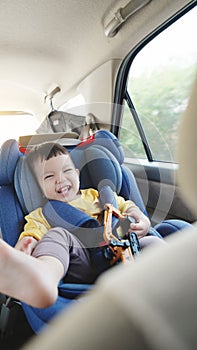 Happy smiling Asian little boy in safety car seat