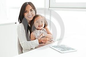 Happy smiling asian mom holding her little daughter