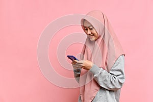 Happy Smiling Asian Muslim woman typing on cellphone