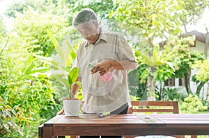 A happy and smiling Asian old elderly man is planting for a hobby after retirement in a home. Concept of a happy lifestyle and