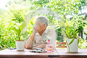 A happy and smiling Asian old elderly man is planting for a hobby after retirement in a home. Concept of a happy lifestyle and
