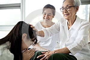 Happy smiling asian senior woman is stroking her child girl head, welcoming her family,loving daughter with her mother comes to