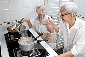 Happy smiling asian senior women showing thumbs up hand sign while cooking delicious stuffed bitter gourd in clear soup,old