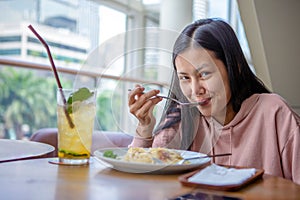 Happy smiling asian woman eating Italian pasta with lemonade in restaurants