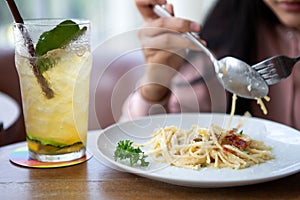 Happy smiling asian woman eating Italian pasta with lemonade in restaurants . close up