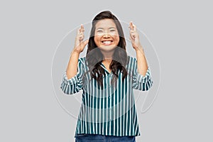 Happy smiling asian woman holding fingers crossed