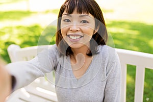 Happy smiling asian woman taking selfie at park