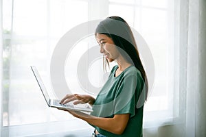 Happy smiling asian young woman using work laptop