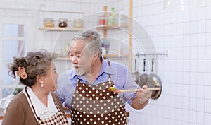 Happy & smiling attractive elderly cute Asian couple in love enjoying cooking healthy salad in kitchen at home together. Happiness