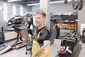 Happy smiling auto mechanic or locksmith with clipboard in workshop