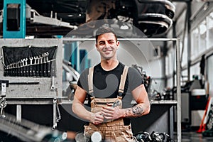 Happy smiling auto mechanic man with wrenches at the workshop