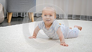 Happy smiling baby boy lying on soft carpet in living room. Concept of child development, happy childhood and fun at