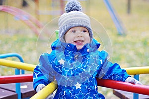 Happy smiling baby boy outdoors in autumn on playground