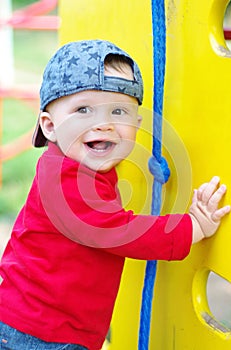 Happy smiling baby boy on playground in summertime