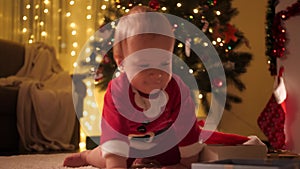 Happy smiling baby boy playing and opening Christmas gift box on Xmas eve. Families and children celebrating winter