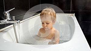 Happy smiling baby boy playing and splashing in the bath while getting clean and washing up