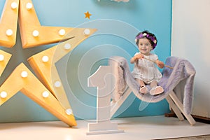 Happy smiling sweet baby girl sitting on armchair with shining light star, Birthday girl,  One year old