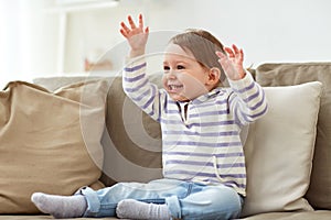 Happy smiling baby girl sitting on sofa at home