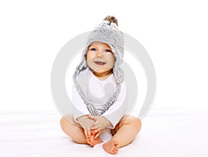 Happy smiling baby in grey knitted hat on white background