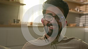 Happy smiling bearded man middle eastern Arabian millennial guy Indian male homeowner sit in domestic kitchen sun in