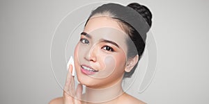 Happy smiling beautiful asian woman using cotton pad cleaning skin