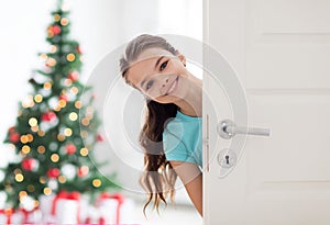 Happy smiling beautiful girl behind door at home