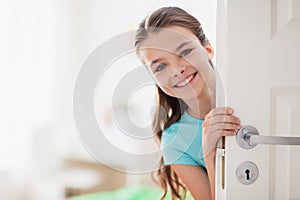 Happy smiling beautiful girl behind door at home