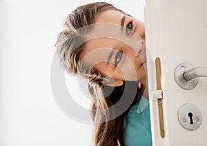 Happy smiling beautiful girl behind door at home