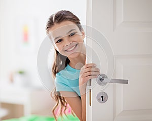 Happy smiling beautiful girl behind door at home