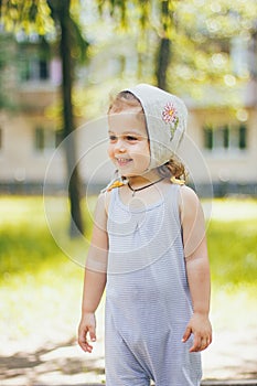 A happy smiling beautiful little girl in a striped clothes and sun hat in sunny park outdoors