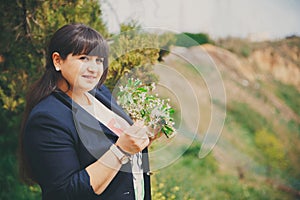 Happy smiling beautiful overweight young woman in dark blue jacket outdoors with flowers. Confident fat young woman. Xxl woman