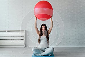 Happy smiling beautiful pregnant woman exercising at home with pilates ball