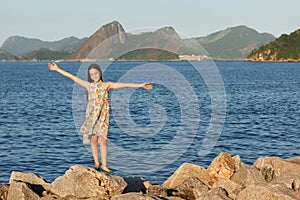 Happy smiling beautiful teen girl standing on stones with long b photo