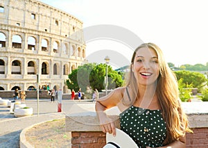 Happy smiling beautiful tourist girl in Rome with Colosseum on the background at sunset. Summer holidays in Italy