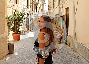 Happy smiling beautiful woman in flowered summer dress walking joyful and cheerful in Syracuse, Italy. Pretty sexy tanned fashion