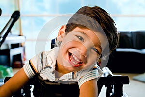 Happy smiling biracial disabled little boy standing in walker